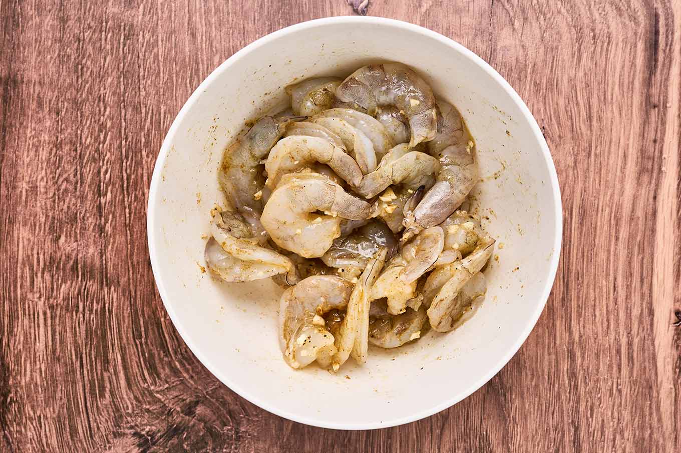 Raw shrimp marinating in olive oil, lime juice, garlic, and cumin before being saut&eacute;ed for shrimp roll sandwiches.