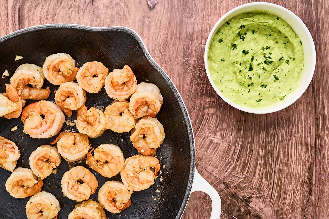 Shrimp rolls with avocado mayo being prepared; saut&eacute;ed shrimp in a cast iron pan and a dish of avocado cilantro mayonnaise to the side.