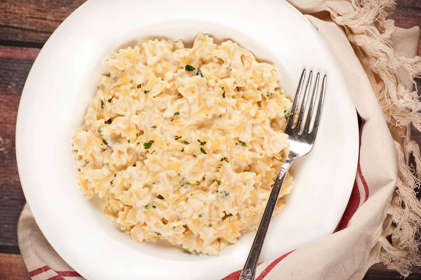 A bowl of cottage cheese and fontina mac and cheese on a rustic, brown tabletop.