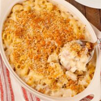 French macaroni and cheese casserole with crisp panko topping and creamy cheese sauce being served from baking dish.