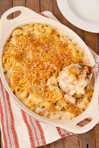 French macaroni and cheese casserole with crisp panko topping and creamy cheese sauce being served from baking dish.