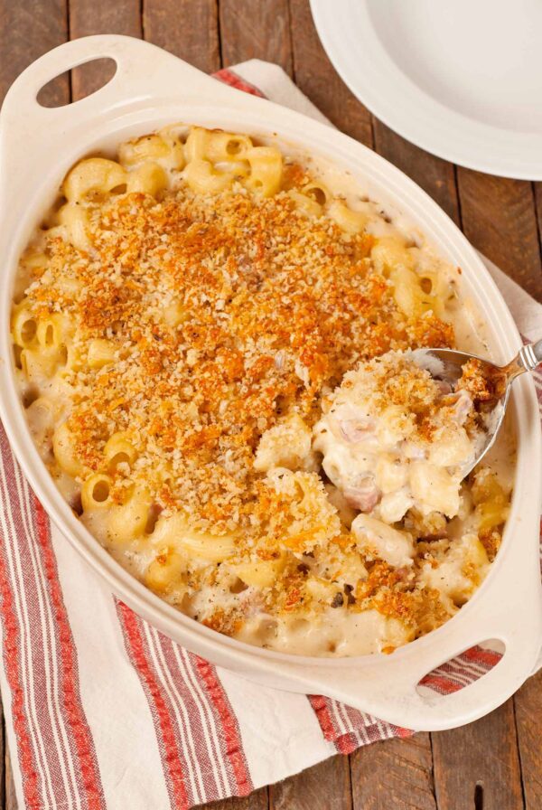 French macaroni and cheese casserole with crisp panko topping and creamy cheese sauce being served from baking dish.