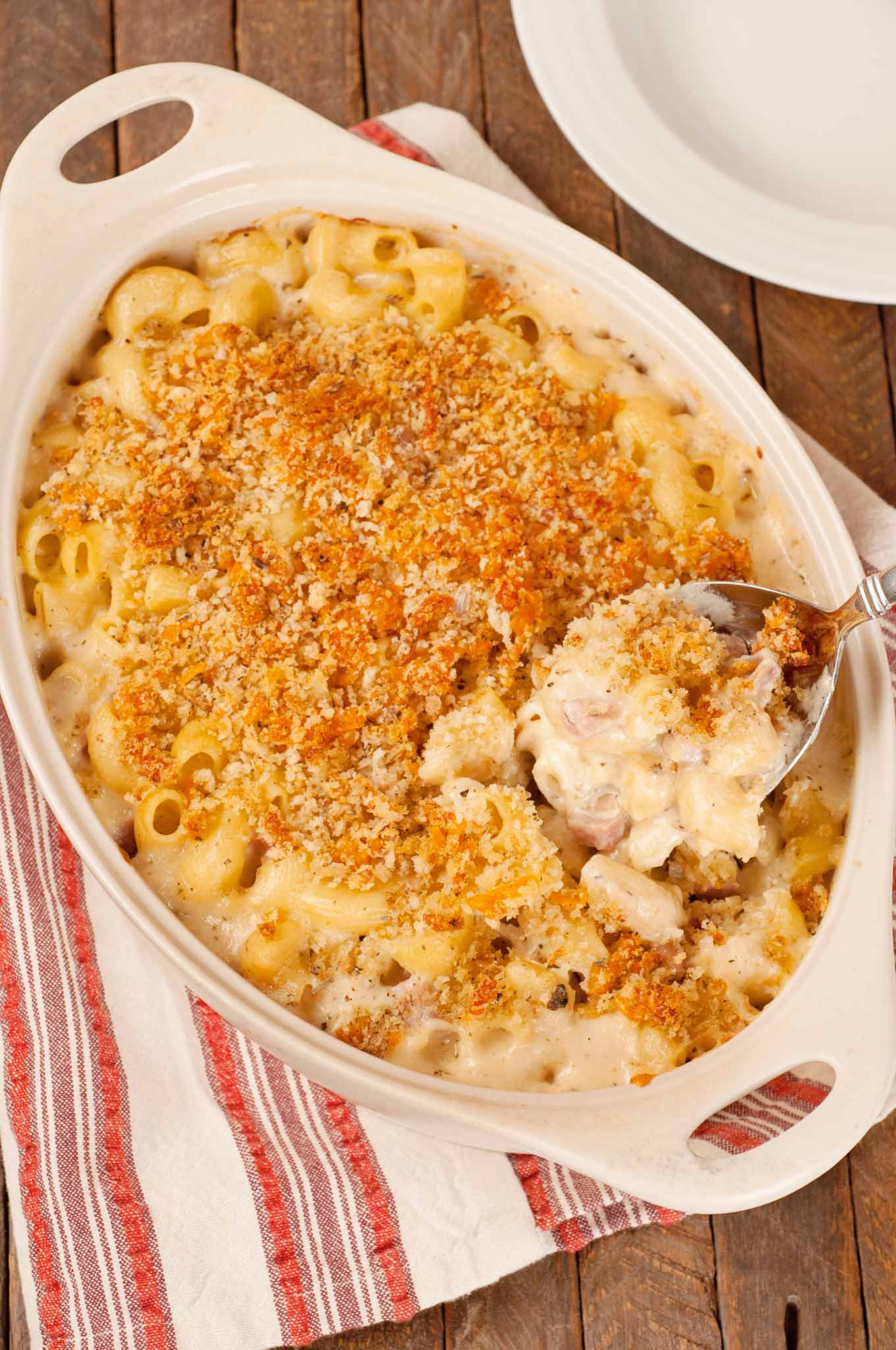 French macaroni and cheese casserole with crisp panko topping and creamy cheese sauce being served from baking dish.