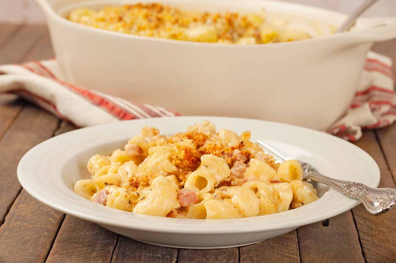 Serving of French macaroni and cheese with ham and toasted panko topping plated in shallow bowl.