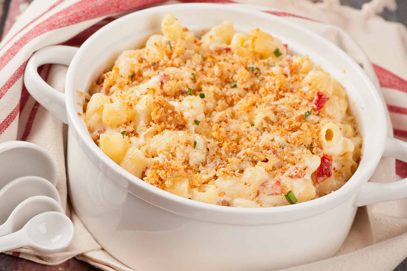 Goat cheese and sun-dried tomato mac and cheese with toasted garlic breadcrumbs in a white casserole dish.