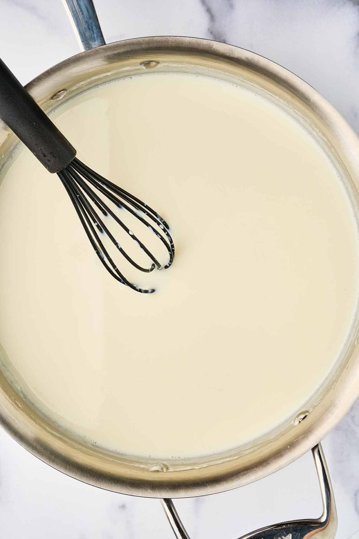 Milk whisked into the roux to make a smooth b&eacute;chamel sauce for stovetop lobster mac and cheese.