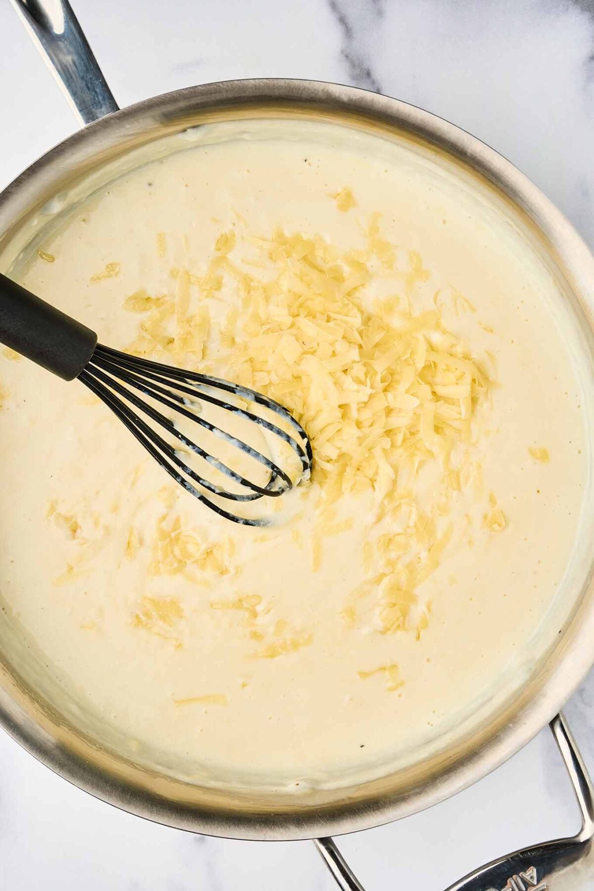 Gruy&egrave;re cheese melting into the b&eacute;chamel sauce for creamy stovetop lobster mac and cheese.