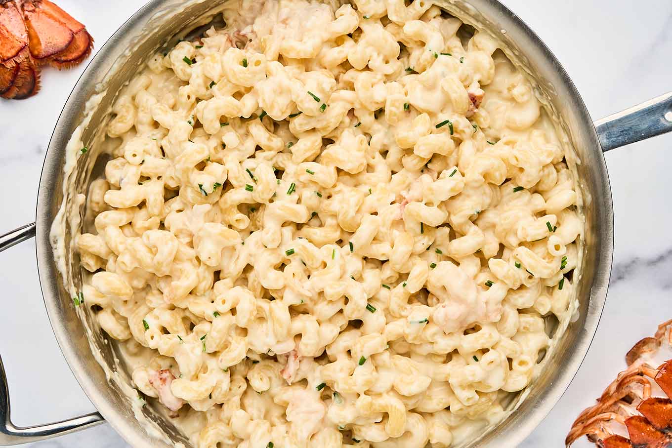 Cooked pasta, lobster, and chives stirred into the creamy cheese sauce for stovetop lobster mac and cheese.