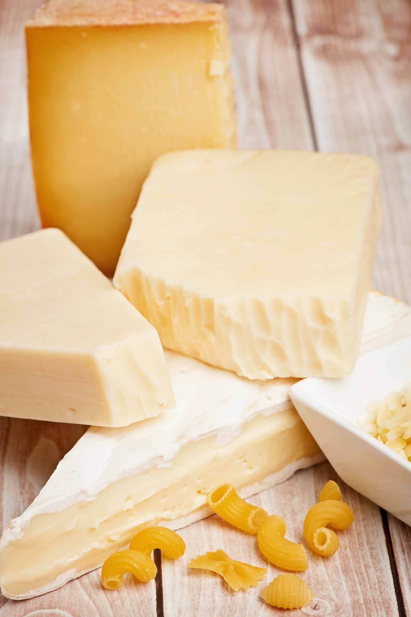 Selection of cheeses including Brie, Gruyère, Asiago, and fontina for homemade macaroni and cheese.