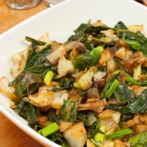 A serving bowl of saut&eacute;ed cabbage and kale, salt and pepper shakers in the background.