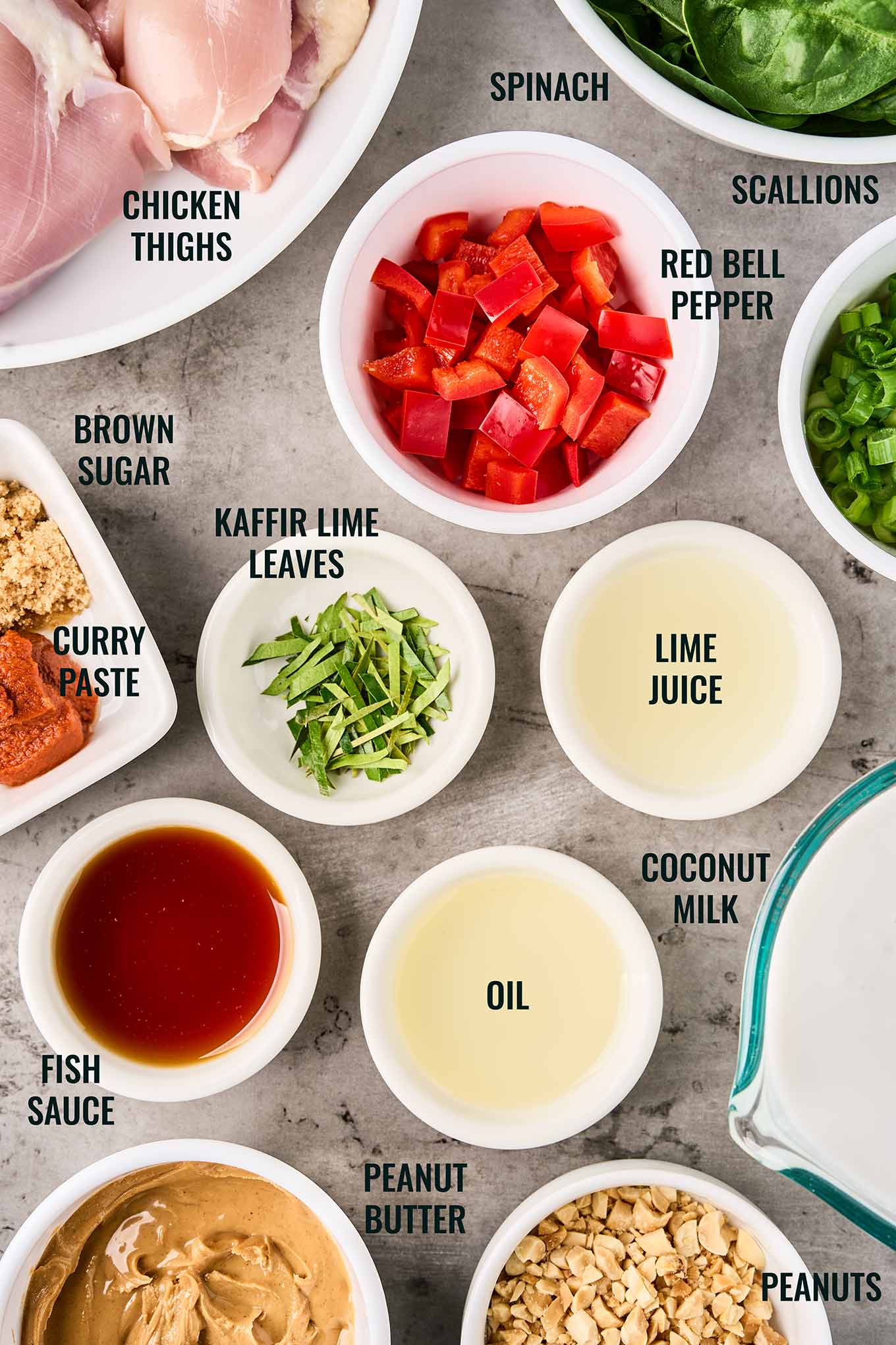 Ingredients for Thai peanut curry including chicken thighs, coconut milk, red curry paste, spinach, lime juice, and peanuts.