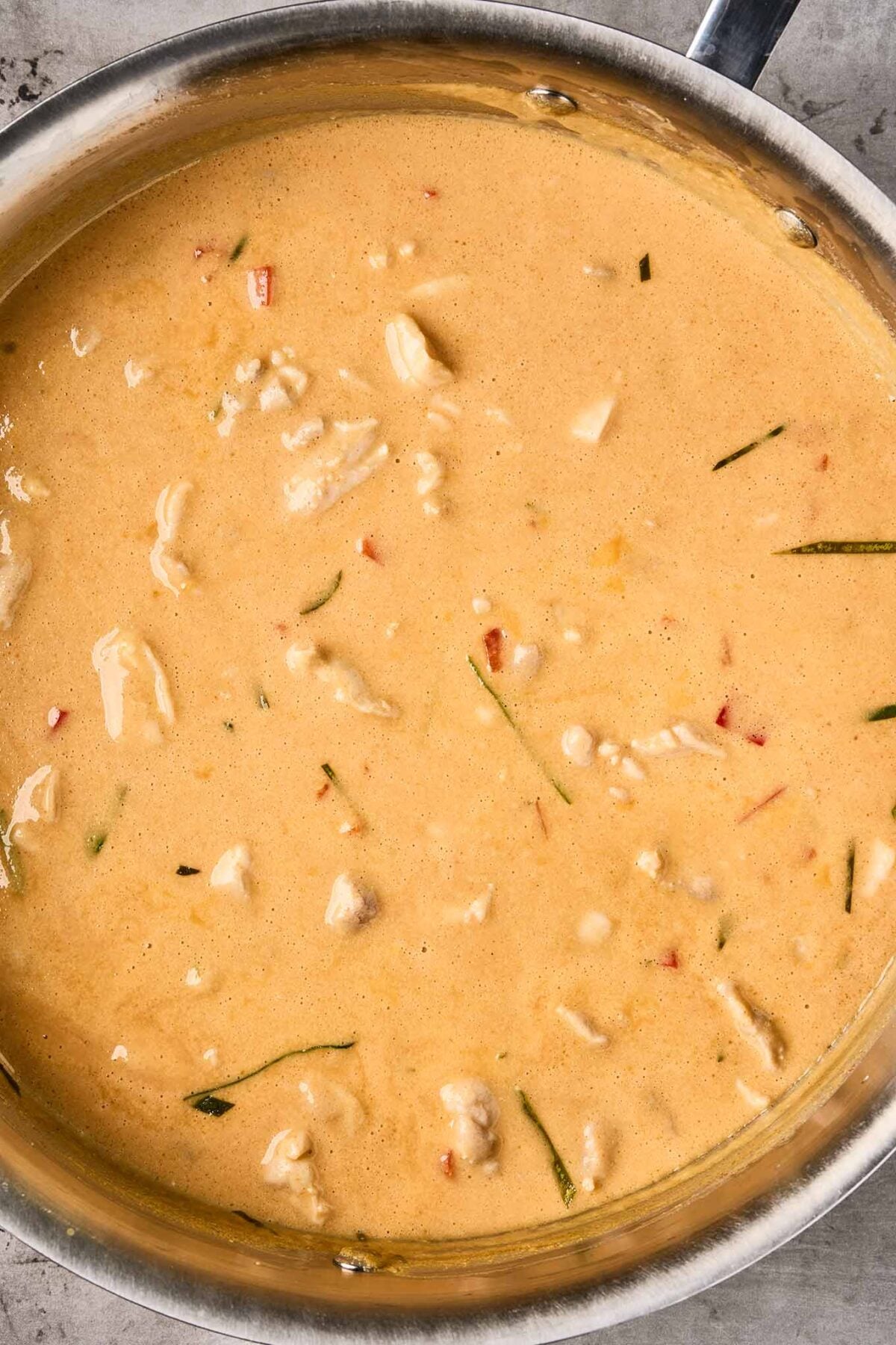 Chicken simmering in creamy Thai peanut curry sauce with coconut milk, red curry paste, and kaffir lime leaves.