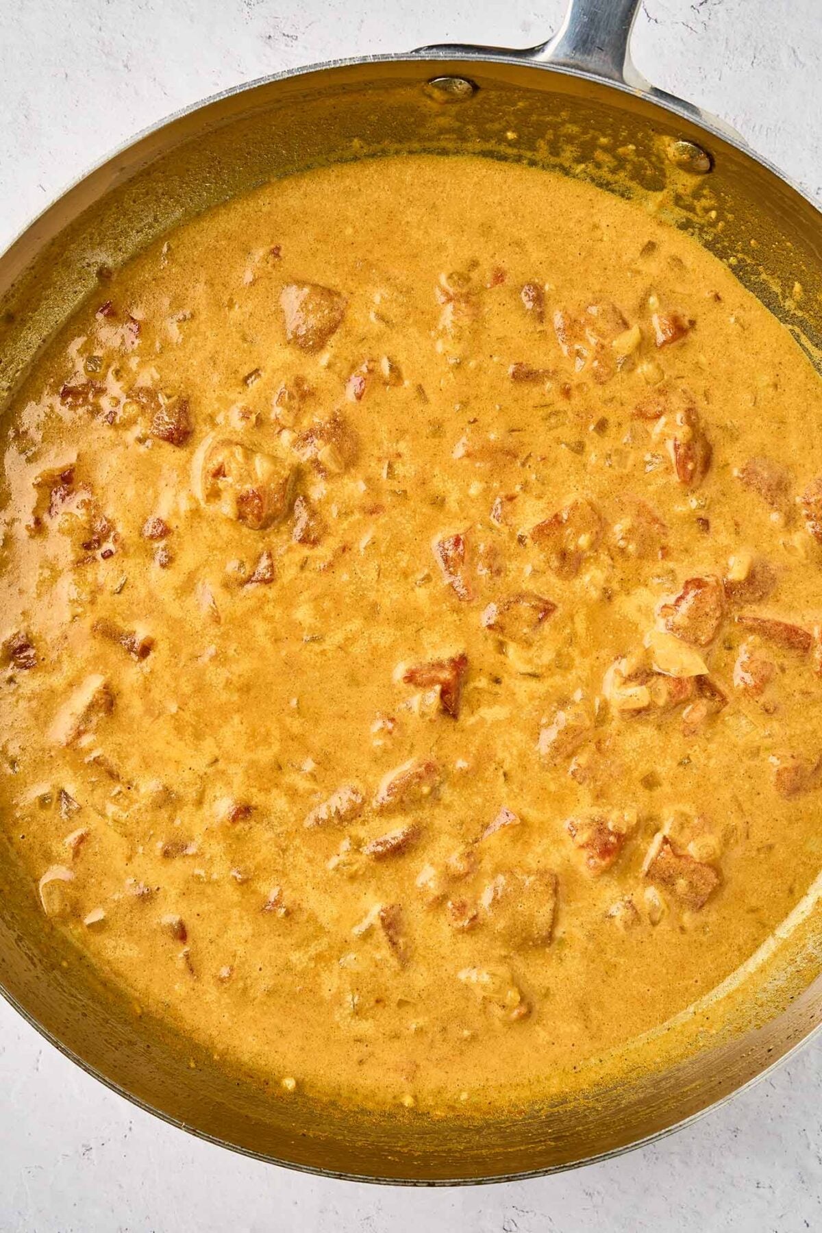 Coconut curry sauce simmering with garlic, ginger, spices, tomatoes, and coconut milk before adding the salmon.