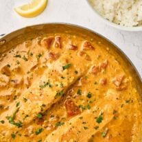 Coconut curry salmon in a skillet with creamy coconut curry sauce, diced tomatoes, and fresh cilantro.