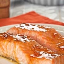 Orange marmalade and bourbon glazed salmon fillets coated in a glossy citrus glaze on a white plate.