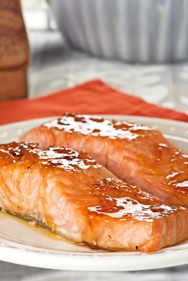 Orange marmalade and bourbon glazed salmon fillets coated in a glossy citrus glaze on a white plate.