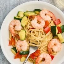 Shrimp and zucchini pasta with linguine, red bell pepper, and tender shrimp served in a shallow bowl.