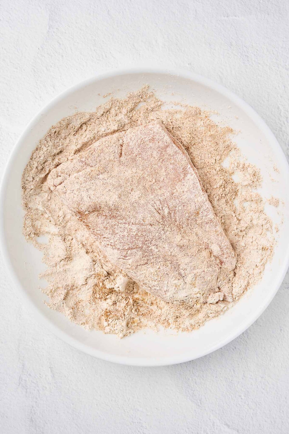 Chicken breast coated in seasoned flour for creamy cilantro lime chicken.
