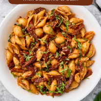 Sun-dried tomato pasta with balsamic and basil served in a white bowl, garnished with fresh basil.