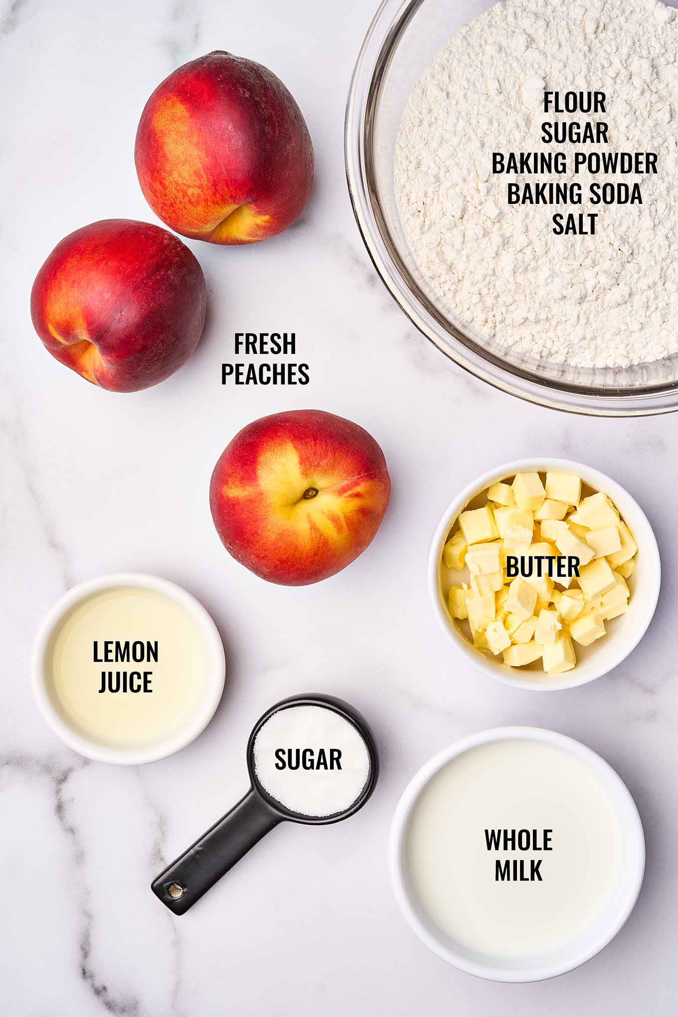 Ingredients for fresh peach cobbler, including peaches, flour mixture, butter, lemon juice, sugar, and whole milk.