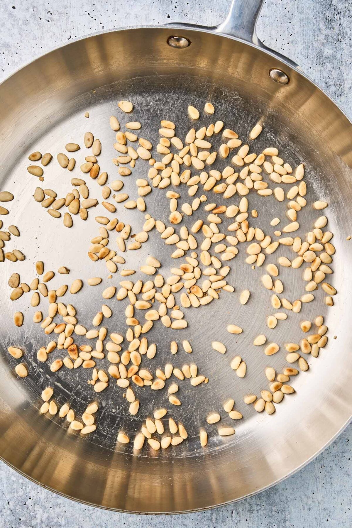 Pine nuts dry-toasting in a skillet until lightly golden.