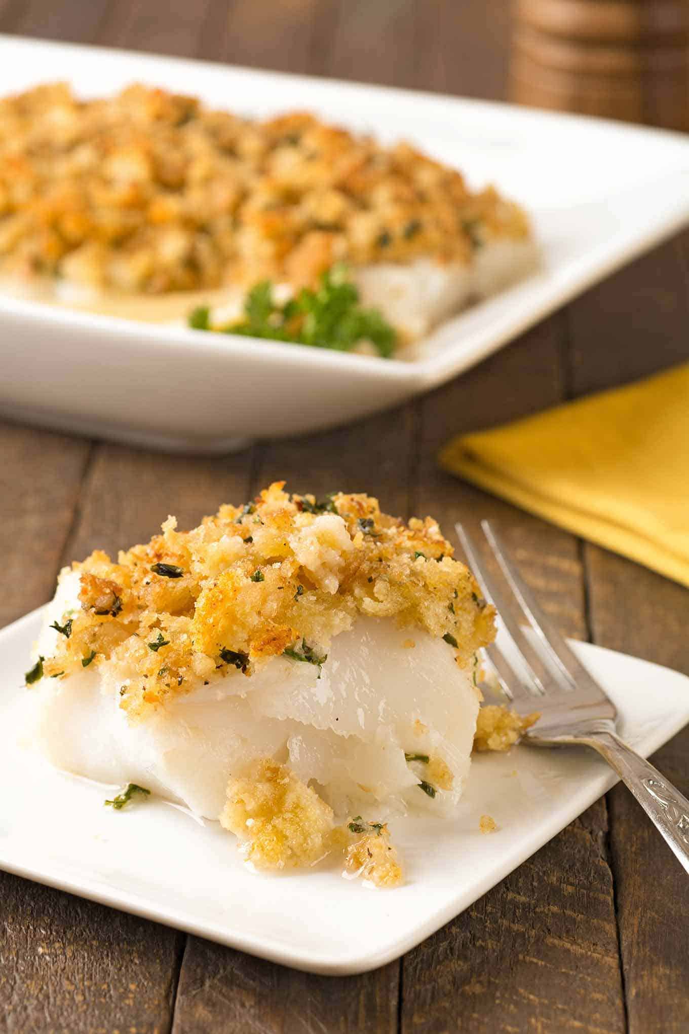 A serving of baked cod topped with a mixture of buttered crumbs, garlic, and parsley.