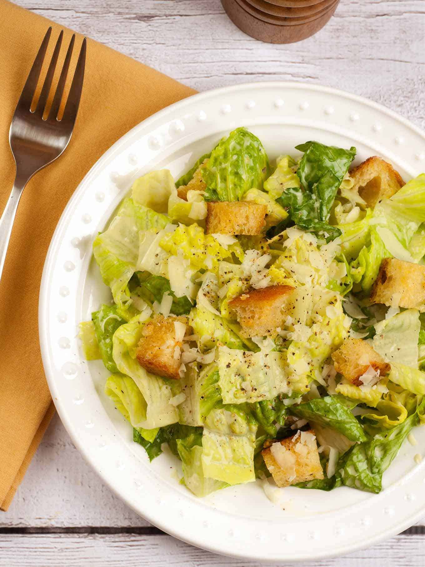 A single serving of Caesar salad topped with croutons.