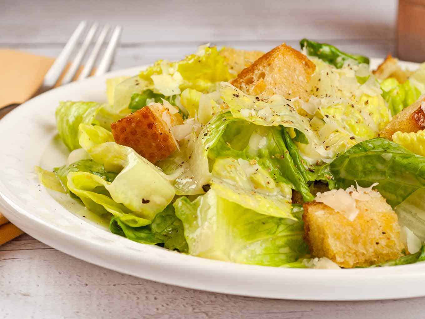 A serving of easy-to-make Caesar salad topped with garlic butter croutons and grated Parmesan cheese.