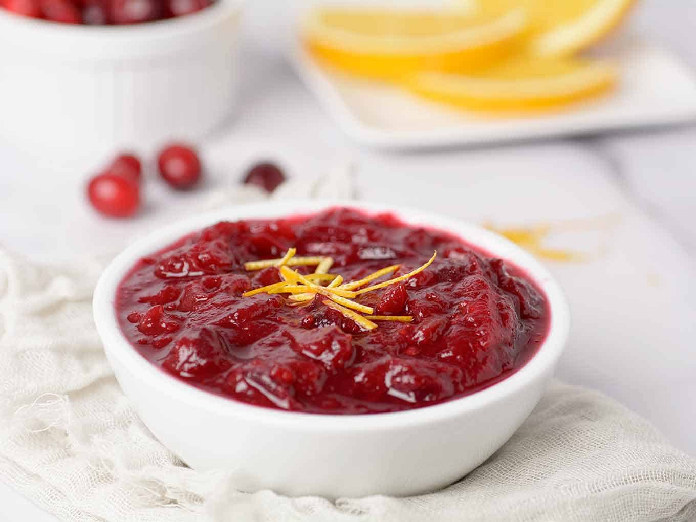 Bowl of homemade cranberry sauce garnished with fresh orange zest.