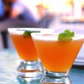 Two Cuban peach cocktails in stemless martini glasses, garnished with fresh mint.