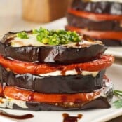 Slices of roasted eggplant, fresh mozzarella, and tomatoes stacked in alternating layers and topped with fresh basil pesto.