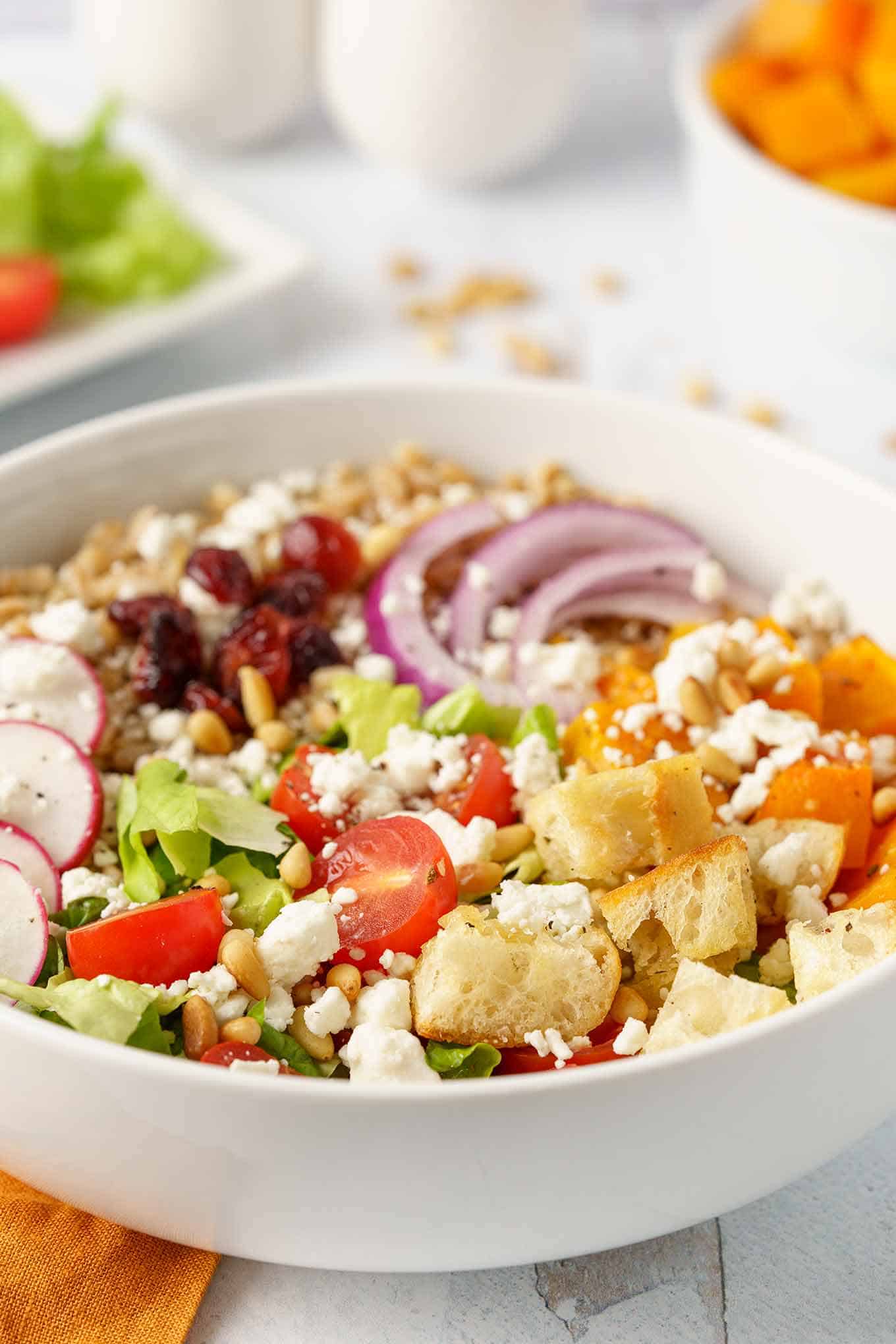 Individual portion of farro salad in a bowl including croutons, cherry tomatoes, salad greens, and other toppings