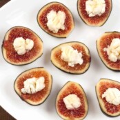 A serving plate filled with fresh figs stuffed with creamy goat cheese.