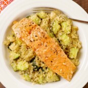 An overhead view of a bowl of quinoa combined with roasted zucchini and topped with a roasted, honey-glazed salmon fillet.