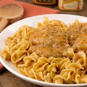 Creamy chicken paprikash featuring tender chicken thighs in a smooth, paprika-infused sauce, nestled on a bed of egg noodles.