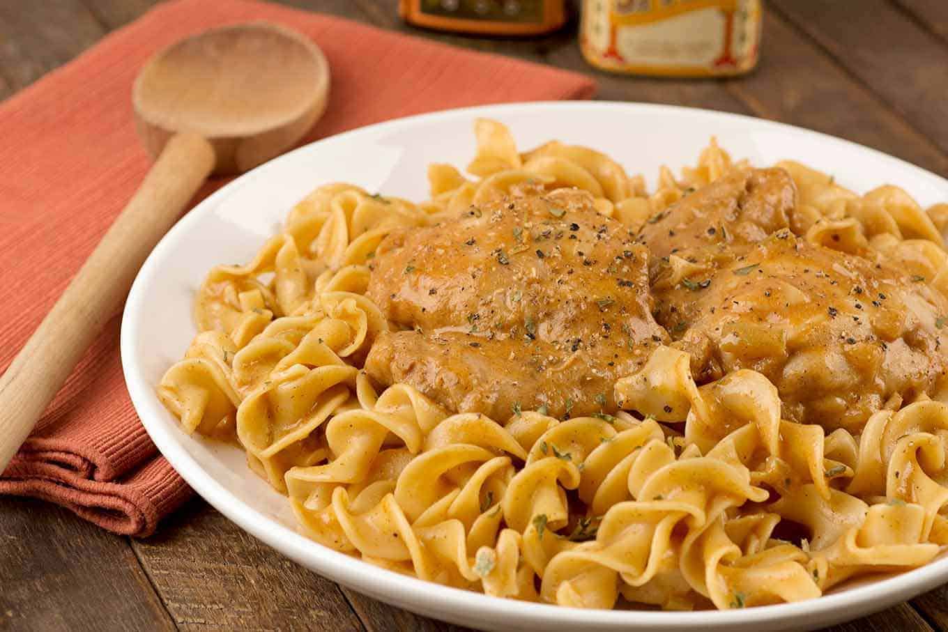 Creamy chicken paprikash featuring tender chicken thighs in a smooth, paprika-infused sauce, nestled on a bed of egg noodles.