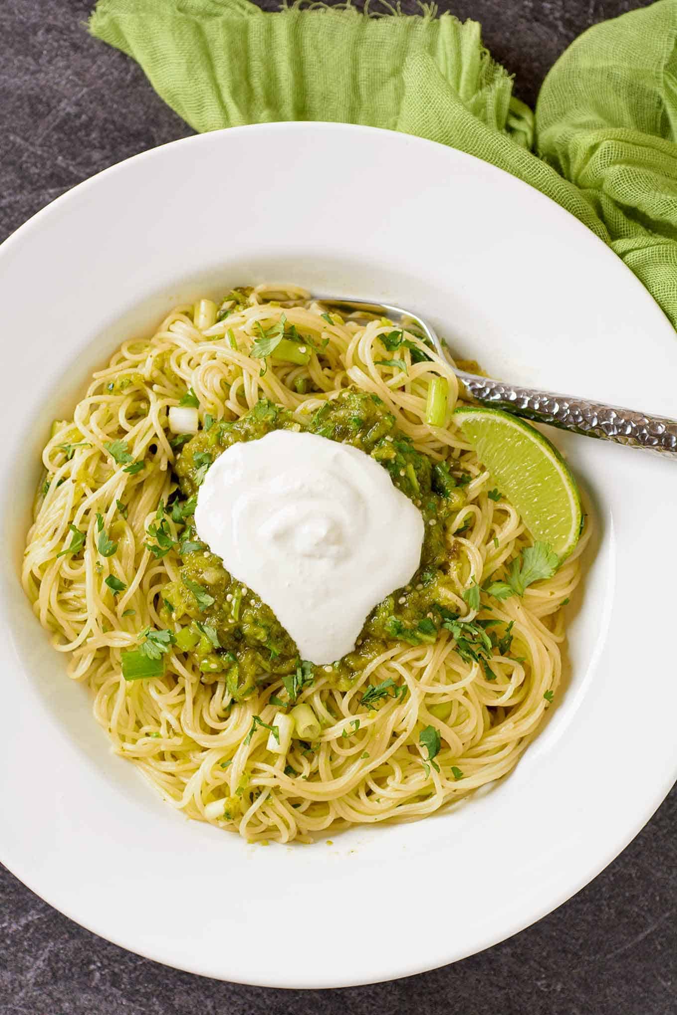 A serving of green spaghetti with a sauce made with roasted tomatillos, poblano peppers, scallions, cilantro, and lime.