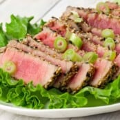 Sesame-crusted tuna slices seared rare, topped with sliced scallions and served on a bed of fresh green leaf lettuce.