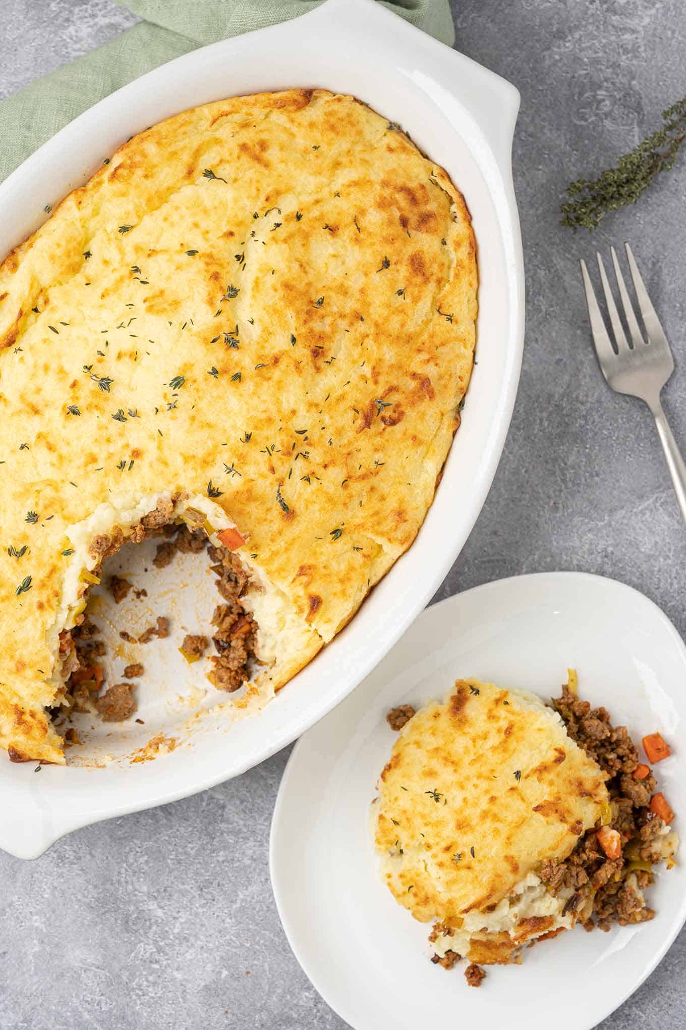 A serving of shepherd's pie on a plate with the casserole in the background.