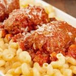 Close up photo of slow-cooked Italian beef braciole served with tomato and red wine sauce over pasta.
