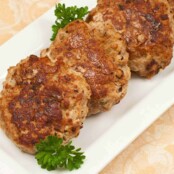 Golden-brown turkey meatloaf patties arranged on a white rectangular platter, garnished with fresh parsley.