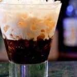 White Russian cocktail served over ice in a short glass, with layers of cream and coffee liqueur swirling together.
